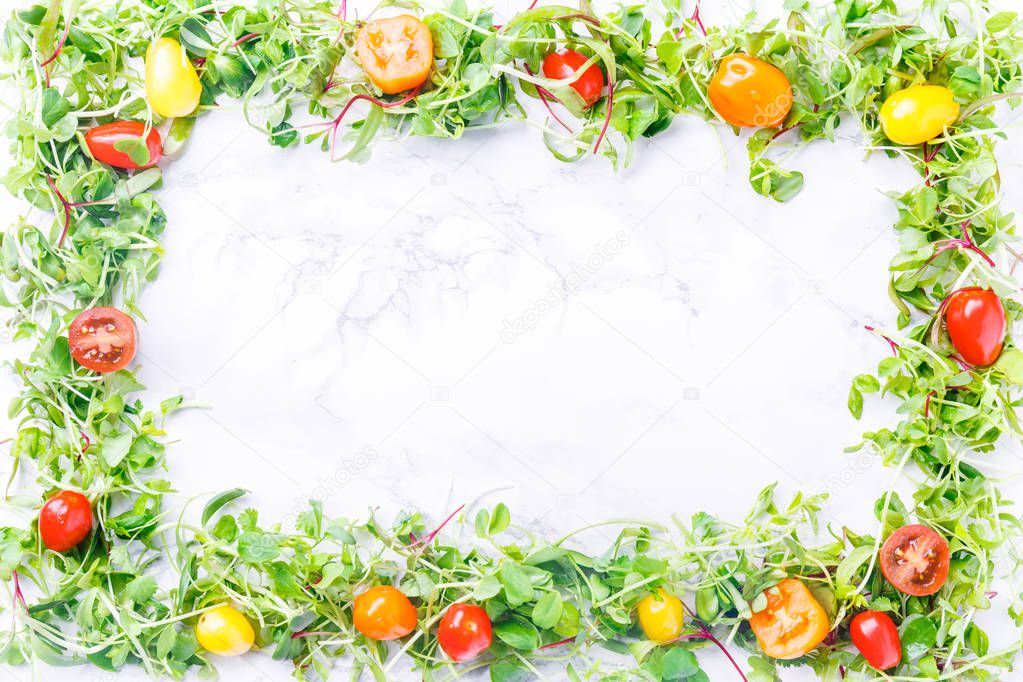 Sprouted baby greens frame with cherry tomatoes. Superfood snack concept. Horizontal