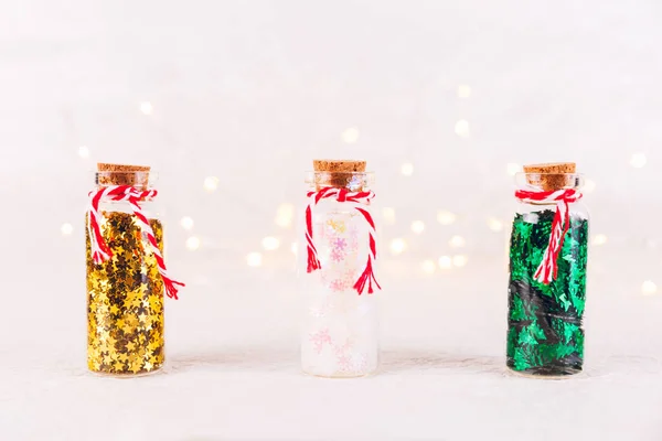 Скляні Пляшки Блискучою Конфетті Білому Тлі Боке Світлами Свято Різдва — стокове фото