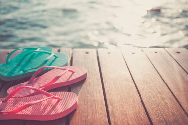 Gün batımı sırasında Flip flop, ahşap iskele. Lüks Tatil resort. Tatil kaçamağı kavramı. Yatay, seçmeli soğuk tonlama