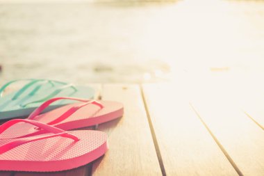 Gün batımı sırasında Flip flop, ahşap iskele. Lüks Tatil resort. Tatil kaçamağı kavramı. Tonlama yatay, sıcak