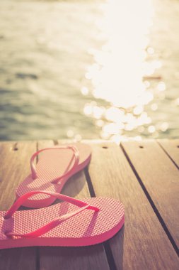 Gün batımı sırasında Flip flop, ahşap iskele. Lüks Tatil resort. Tatil kaçamağı kavramı. Tonlama dikey, sıcak