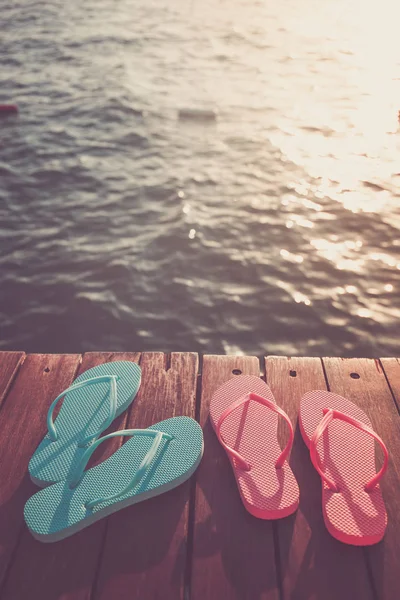 Gün batımı sırasında Flip flop, ahşap iskele. Lüks Tatil resort. Tatil kaçamağı kavramı. Dikey, seçmeli soğuk tonlama