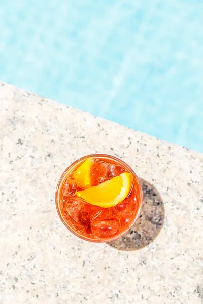 Negroni cocktail  near a pool at the resort bar or suite patio. Luxury resort, vacation, room service concept. Overhead shot. Vertical
