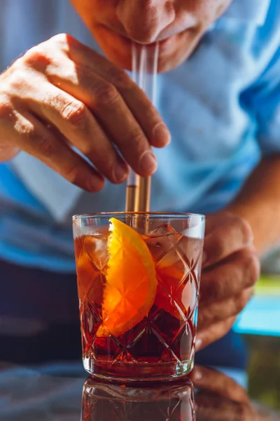 Man drinking negroni cocktail at the resort bar or suite patio. Luxury resort, vacation, room service concept. Vertical
