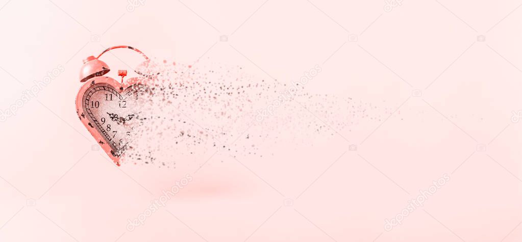 Heart shaped clock dispersing on pink background.  Valentines day and love infitity and duration concept, romance ending. Horizontal, banner wide screen format. Living coral theme - color of the year 2019