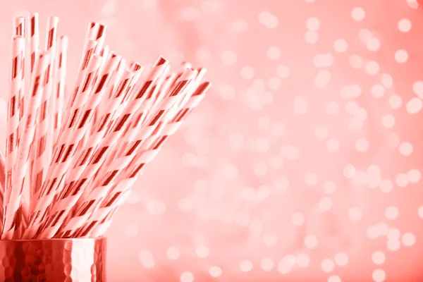 Gold and white paper straws in the golden glass. Christmas concept. Festive holiday party background. Horizontal. Living coral theme - color of the year 2019