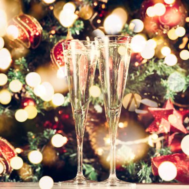 İki bardak şampanya Noel ağacı arka plan ile. Tatil sezonu arka plan. Geleneksel kırmızı ve yeşil Noel dekorasyon ışıklar ile. Tatil partisi. , Sparkles ile kare ve tonda. Festival kalın bokeh