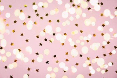 Pembe üzerinde altın yıldız sprinkles. Şenlikli tatil arka plan. Kutlama kavramı. Üstten görünüm, düz yatıyordu. Yatay, cesur ışık bokeh arka plan
