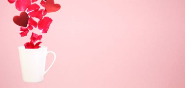 Kahve kupa gül yaprakları ve kalpleri ile levitating. Sürpriz, tatil ve kahve kavramı seviyorum. Minimal sanat eğilim. Düz arka plan. Yatay, geniş ekran başlık biçimi