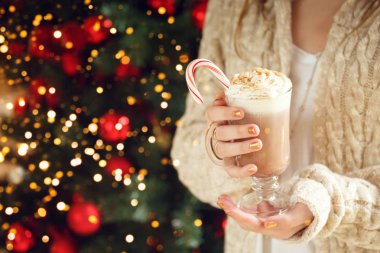 Kız krem şanti ve nane şeker kamışı ile kakao tutan. Noel konsepti. Şenlikli tatil kutlaması bokeh
