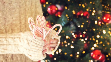 Nane şekeri şeker kamışı yığını tutan kız. Noel tatili konsepti. Tatil geçmişi. Şenlikli tatil kutlaması bokeh