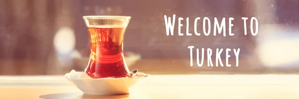 Hot turkish tea outdoors near glass wall. Turkish tea and traditional turkish culture concept. Welcome to Turkey text