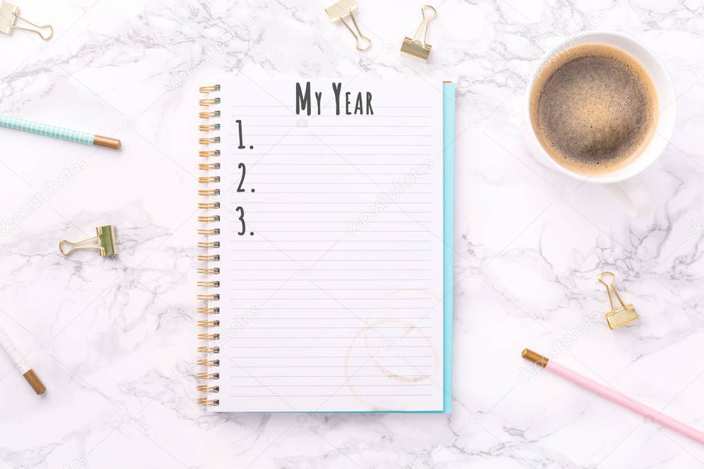 Festive golden stationary and coffee on white marble background. My Year wording. Copy space