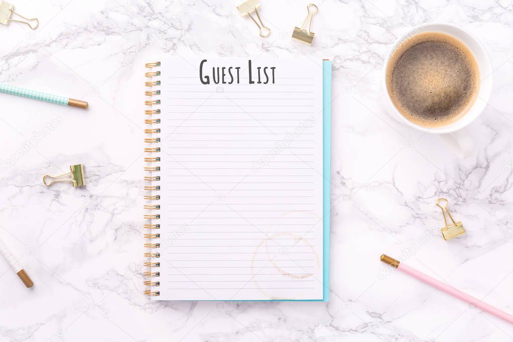 Festive golden stationary and coffee on white marble background. Guest List wording. Copy space