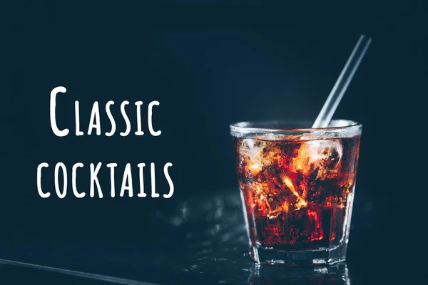 Cuba libre cocktail at the bar stand. Dark background. Classical cocktails wording — Stock Photo, Image