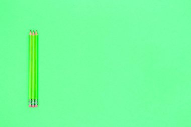 Neon yeşili arka plan üzerine kalemler. Okul konseptine geri dön
