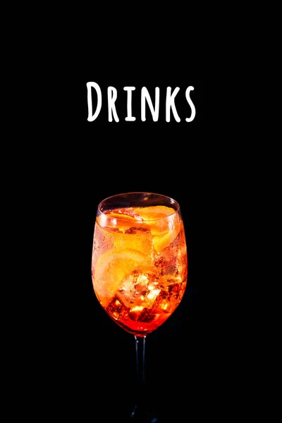 Стильний алкогольний коктейль з аперитивом з апельсиновим шматочком на чорному тлі. Напої написання — стокове фото