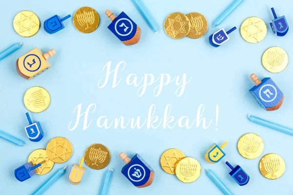 Fundo azul com dreidels, velas menora e moedas de chocolate com Happy Hanukkah redação — Fotografia de Stock