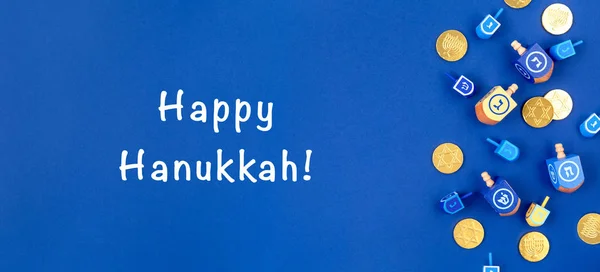 Fondo azul oscuro con dreidels y monedas de chocolate y la redacción feliz Hanukkah. Hanukkah y judaic concepto de vacaciones . — Foto de Stock