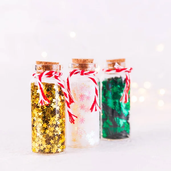 Скло пляшки з блискучим конфетті на білому тлі з бокевим світлом. Святкування Різдва і Новий рік — стокове фото