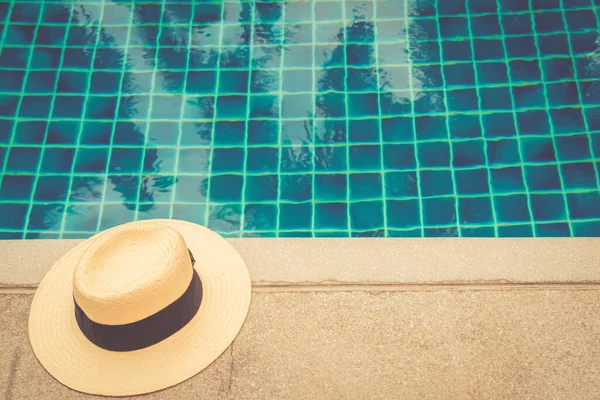 Sombrero de paja en el borde de la piscina con reflejos de palma en el agua — Foto de Stock