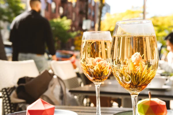 Bloeiende bloementhee geserveerd in een wijnglas, in het trendy outdoor cafe Stockafbeelding