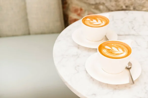 Cups of cappuccino on the white marble table in a modern cafe