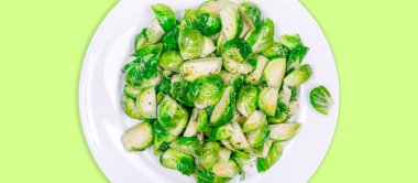 Katı renk damlasında beyaz bir tabakta hafif kızarmış Brüksel lahanası.