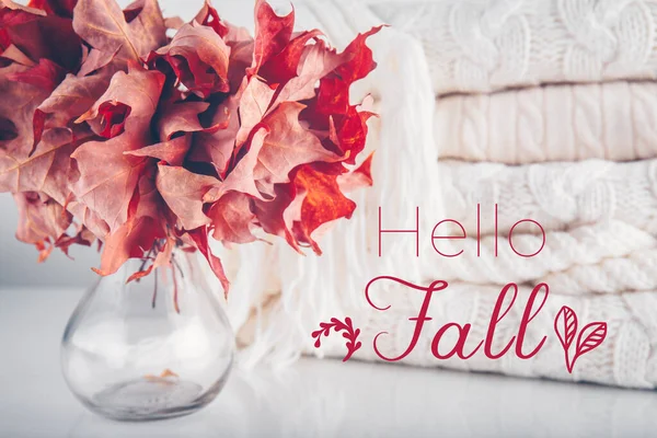 Gefallene Blätter in einer Vase mit einem Haufen weißer Strickwollkleidung mit der Aufschrift Hallo Herbst — Stockfoto