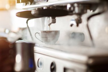 Barista, arka planda buharlı klasik bir İtalyan kahve makinesiyle espresso yapıyor..