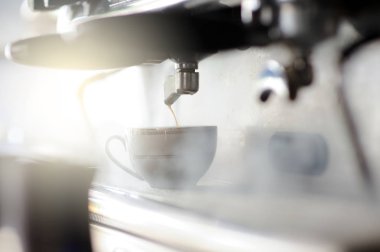 Barista, arka planda buharlı klasik bir İtalyan kahve makinesiyle espresso yapıyor..