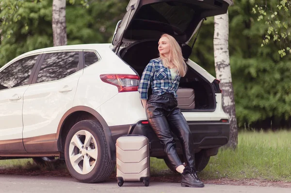 A blonde woman near with luggage