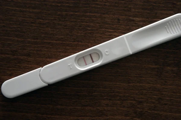 Express pregnancy test showing a positive result, lies on a wooden table