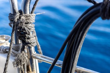 Mavi denize karşı bir gemide krom korkuluk ve iplerden oluşan gemi parçaları.