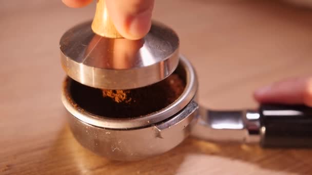 Man tamps fresh grounded coffee in filter holder with tamper. Close up shot of male hand — Stock Video