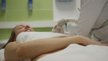 Gülümseyen kadın kanepede profesyonel ekipman ile kozmetik tedavi gets