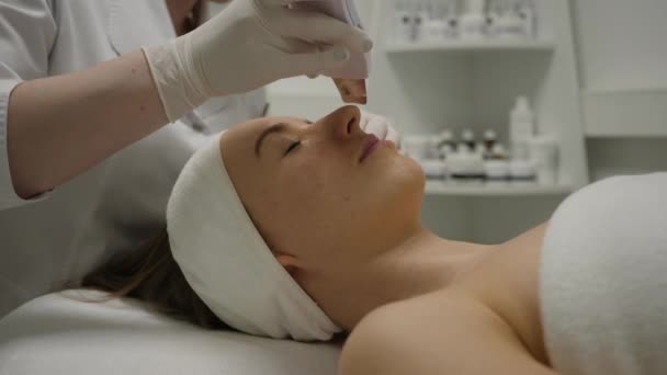 Cosmetologist makes an ultrasonic cavitation face peeling for young woman — Stock Video