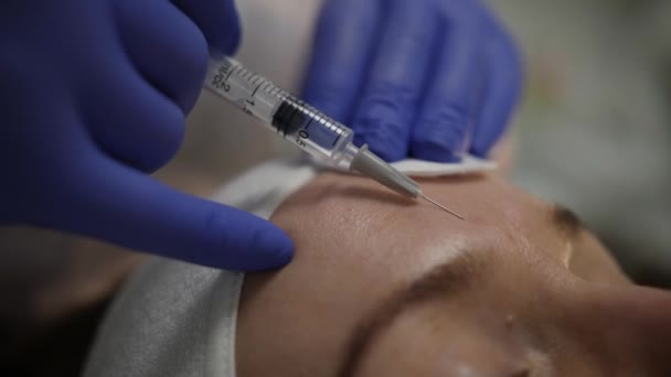 Primer plano de la frente femenina y médicos manos haciendo inyecciones de belleza — Vídeo de stock