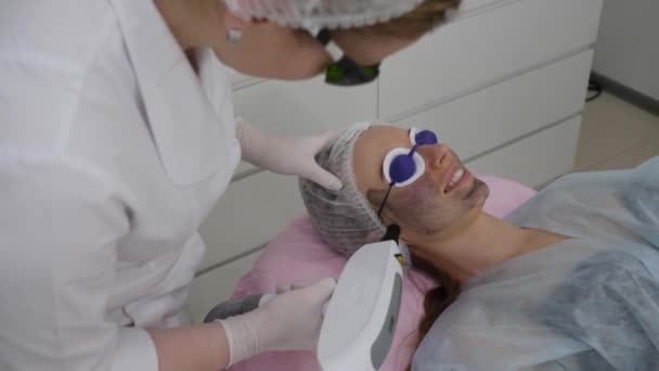 Carbon peeling: laser removes an old skin with carbon fiber layer. Woman and therapist in protective glasses — Stock Video