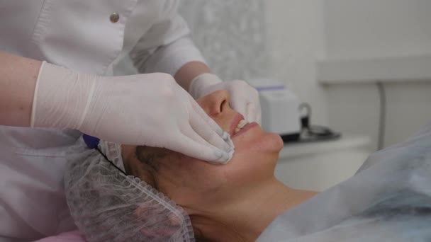 Il cosmetologo toglie il cosmetico da faccia di clienti. Donna ottiene il trattamento di cura della pelle — Video Stock