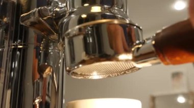 Barista dipsiz filtre kahve makinesi yerleştirir. Adam krom yüzey üzerinde yansıması