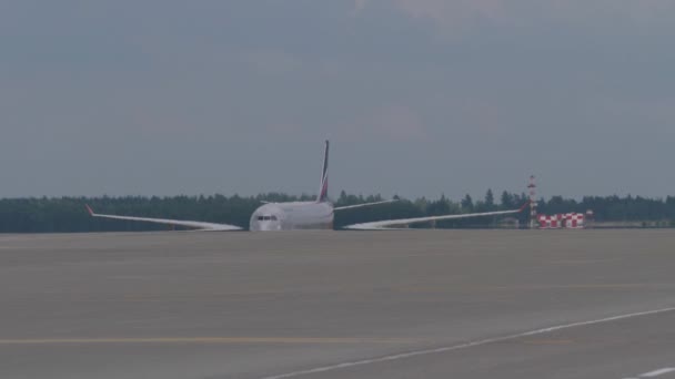 El gran avión de pasajeros se mueve lentamente en la pista. Amplia extensión alas parpadean en el calor neblina — Vídeo de stock