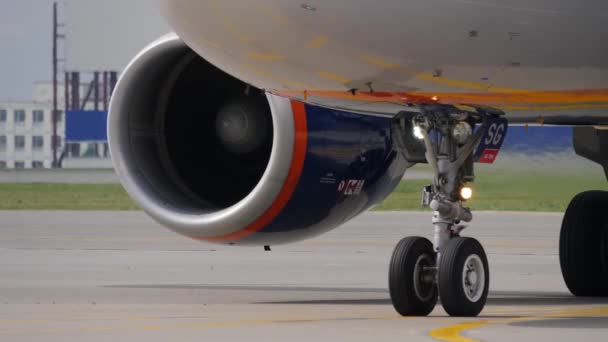 Tren de aterrizaje y motor del avión de pasajeros. El fuselaje refleja el marcado de la calzada — Vídeos de Stock