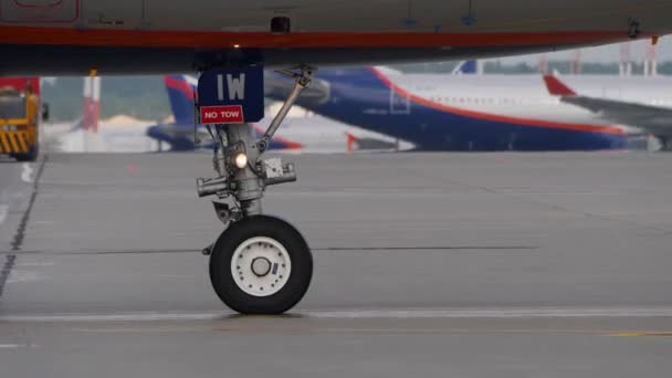 Landningsställ av taxning flygplan. Förgrunden hjulet av flygplan som rör sig på flygplatsen förkläde — Stockvideo