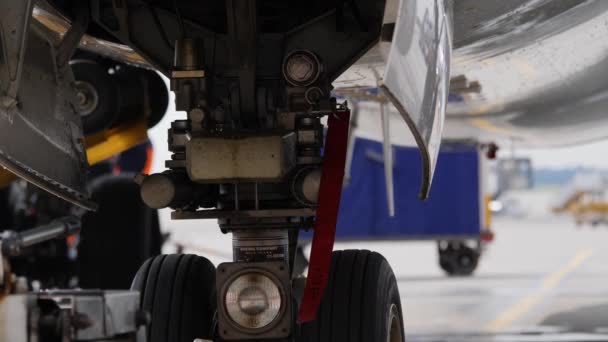 Onderstel van geparkeerde vliegtuig met rode waarschuwing verwijderen voordat vliegen lint — Stockvideo