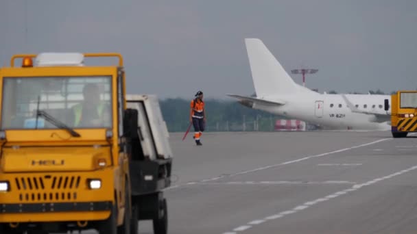 Moskva, Rusko - 25 července 2018: Muž v uniformě z letiště groundcrew chodí na pojezdové dráze mezi podpůrných vozidel. Stanice metra Partizanskaja je jedním z největších v Rusku — Stock video