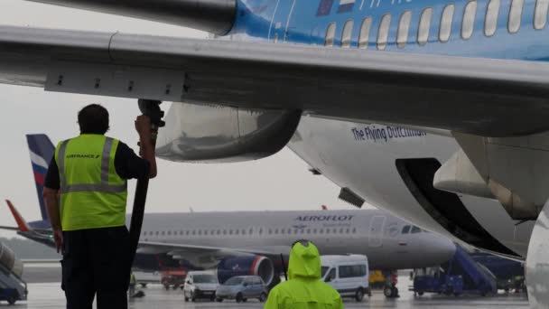 Moskva, Rusko - 25 července 2018: Pracovník technické podpory pozemní refuels Kml letadlo za silného deště v letiště Šeremetěvo — Stock video