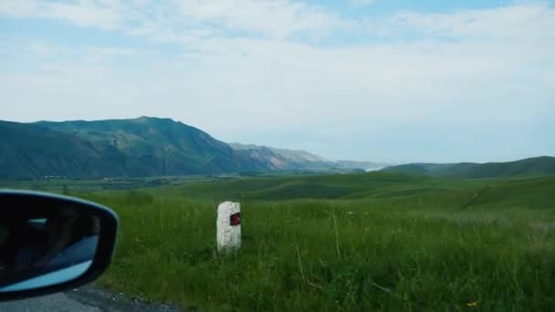 Вид из бокового окна автомобиля, движущегося вдоль холмистой долины в горах — стоковое видео