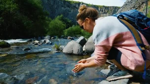 Fiatal gyönyörű nő megmossa a kezét a tiszta hegyi folyó Garni Gorge — Stock videók