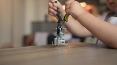 Erkek bebek meccano bisiklet ve iğne-burun pense ile oynuyor. El aletleri yakın çekim